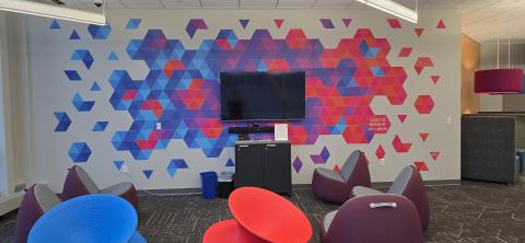 wall with mounted tv with a blue, red, and purple geometric mural behind it. 